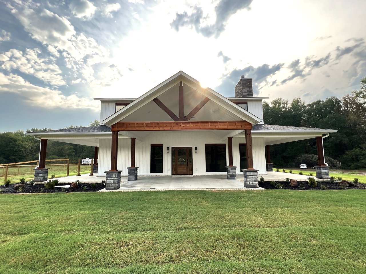 Front porch and timber gable of a white farmhouse beneath a sunlit sky