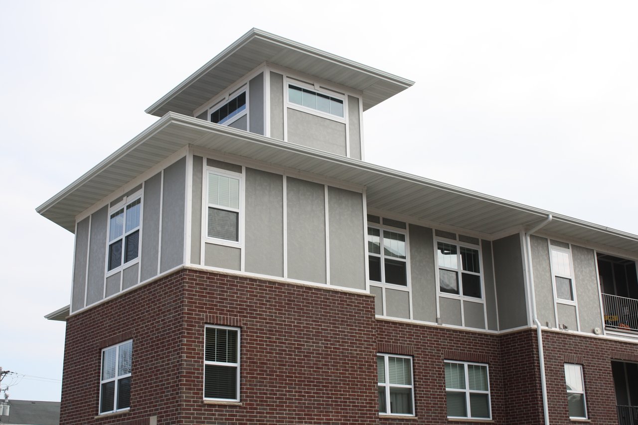 Multifamily building with red brick, gray siding, and large corner windows