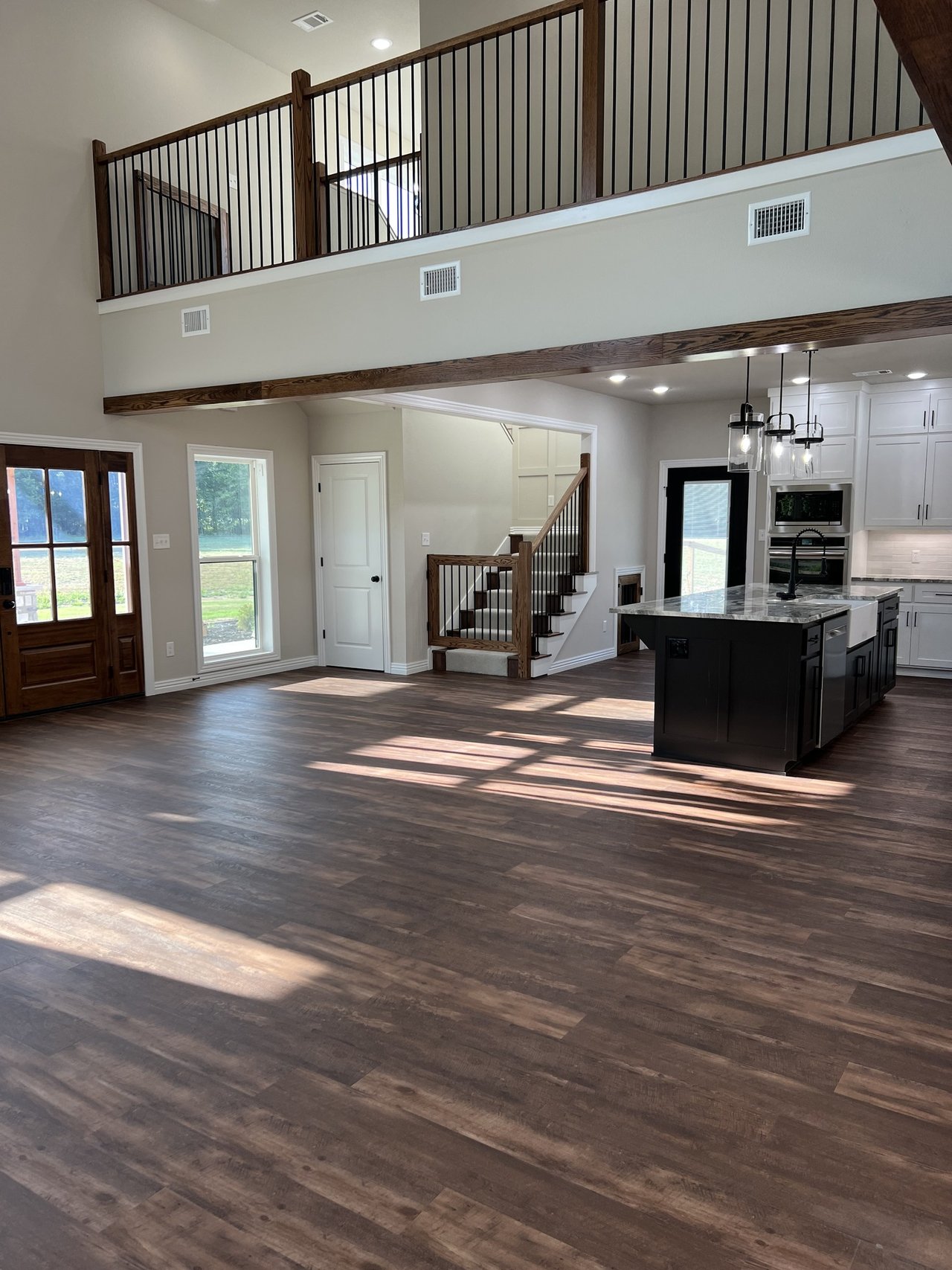 Open-plan home interior with a stairway, upper landing, and dark wood flooring