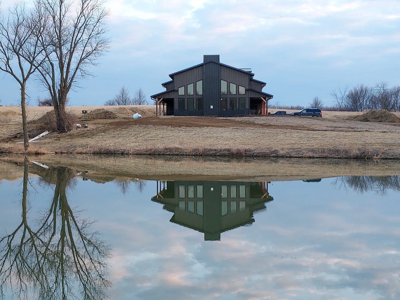 Custom barndominium reflected in a still pond