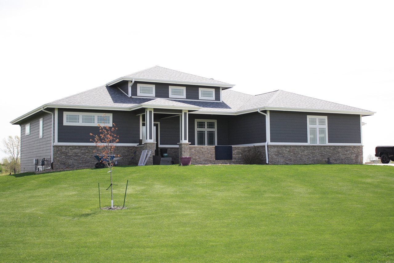 Wide single-story home with a raised central roof and a broad green lawn