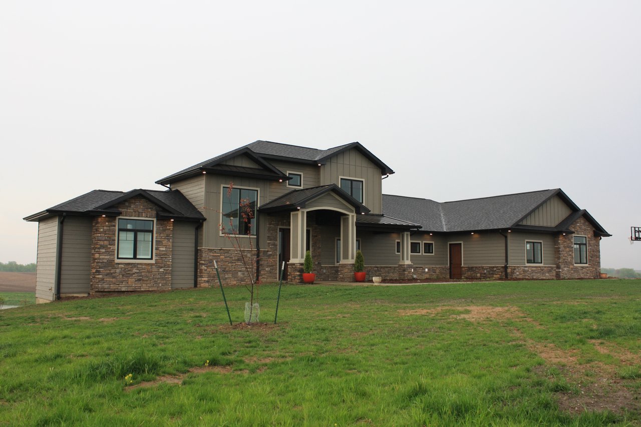 Custom home with stone and green siding, multiple gables, and covered entry